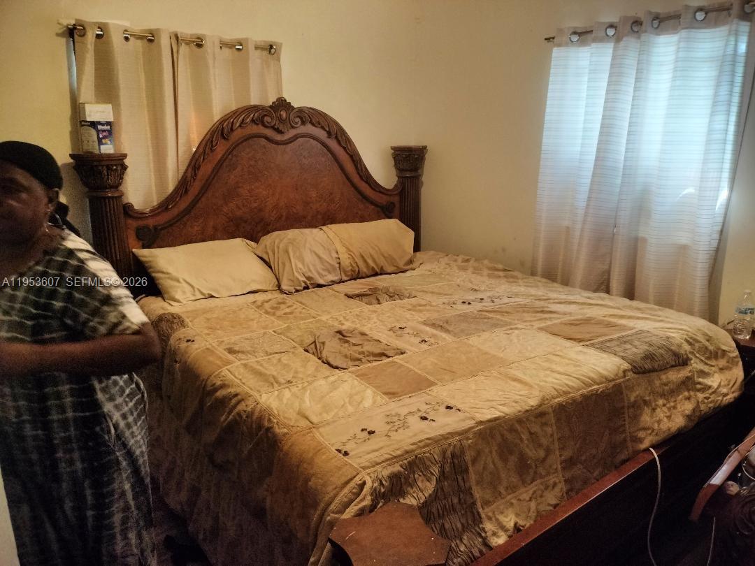 A bedroom features a large wooden headboard, a patchwork quilt, and curtains over a window — 3206 SW 47th Ave, West Park FL 33023, WEST PARK, FL