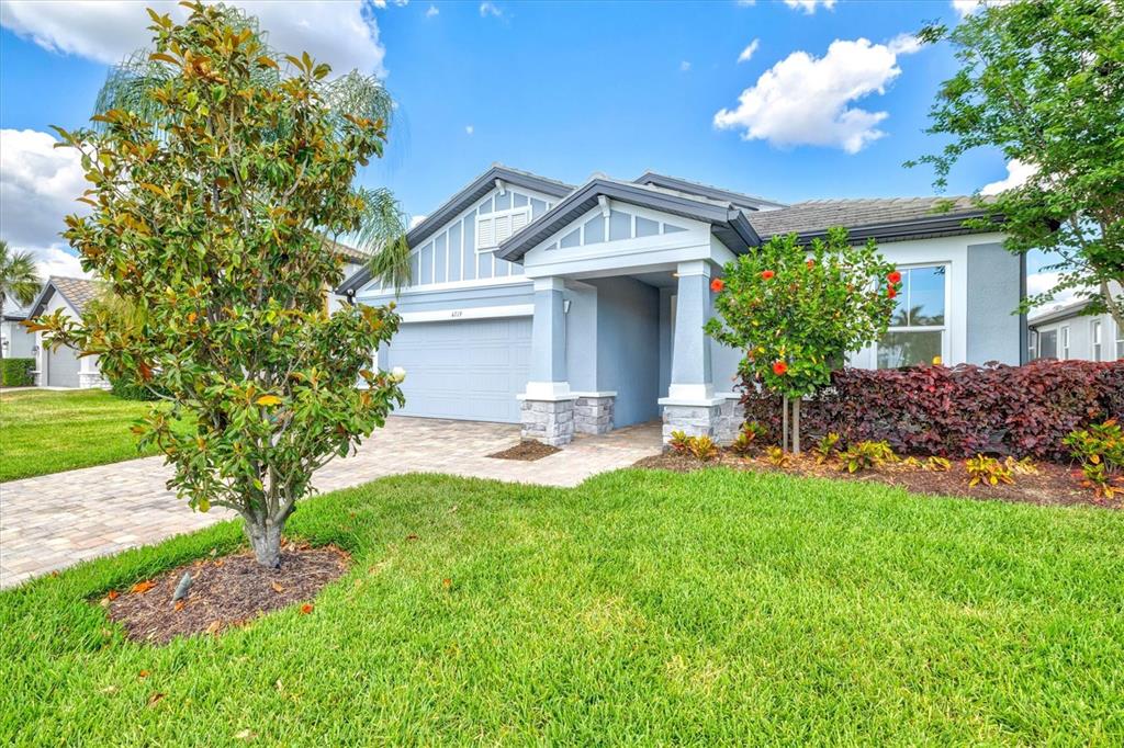 A single-story house with a blue exterior, stone accents, a paved driveway, and front landscaping — 4719 WINSOME WAY, BRADENTON, FL