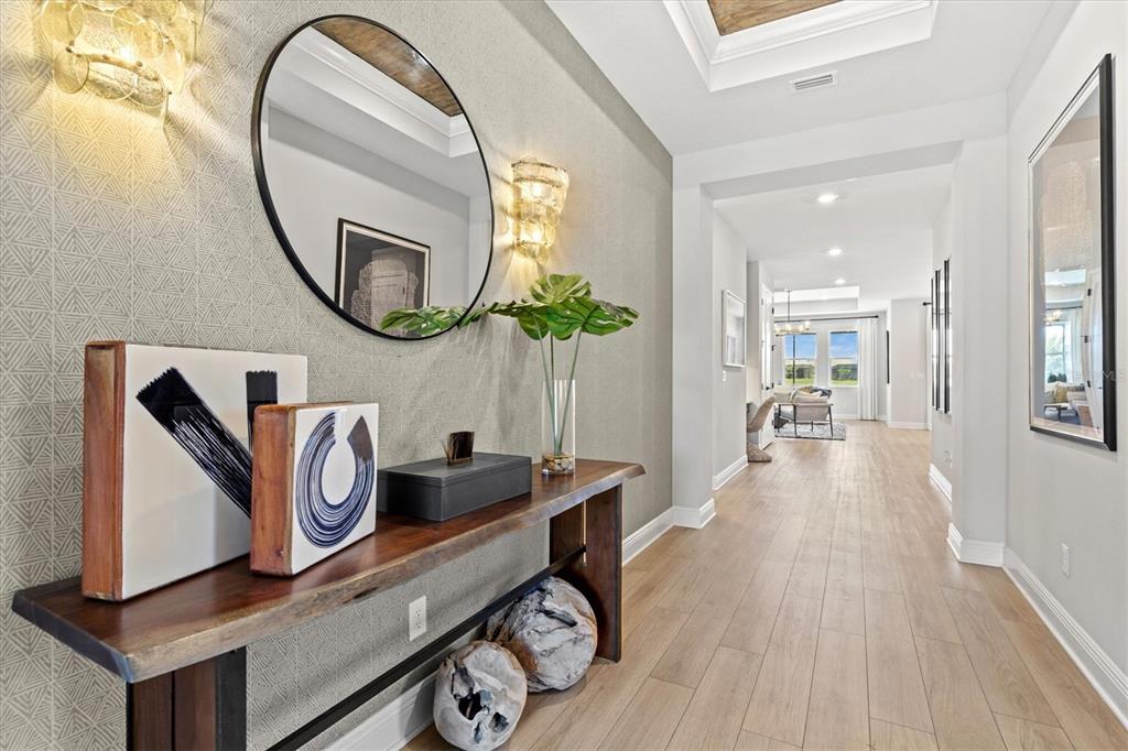 A modern entryway features a wood console table, a round mirror, and patterned wallpaper — 4719 WINSOME WAY, BRADENTON, FL