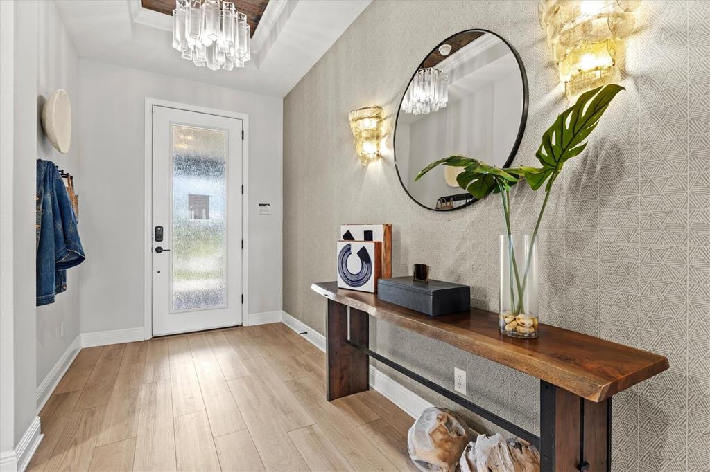 A modern entryway features a live-edge wood console table, patterned wallpaper, and a round mirror — 4719 WINSOME WAY, BRADENTON, FL