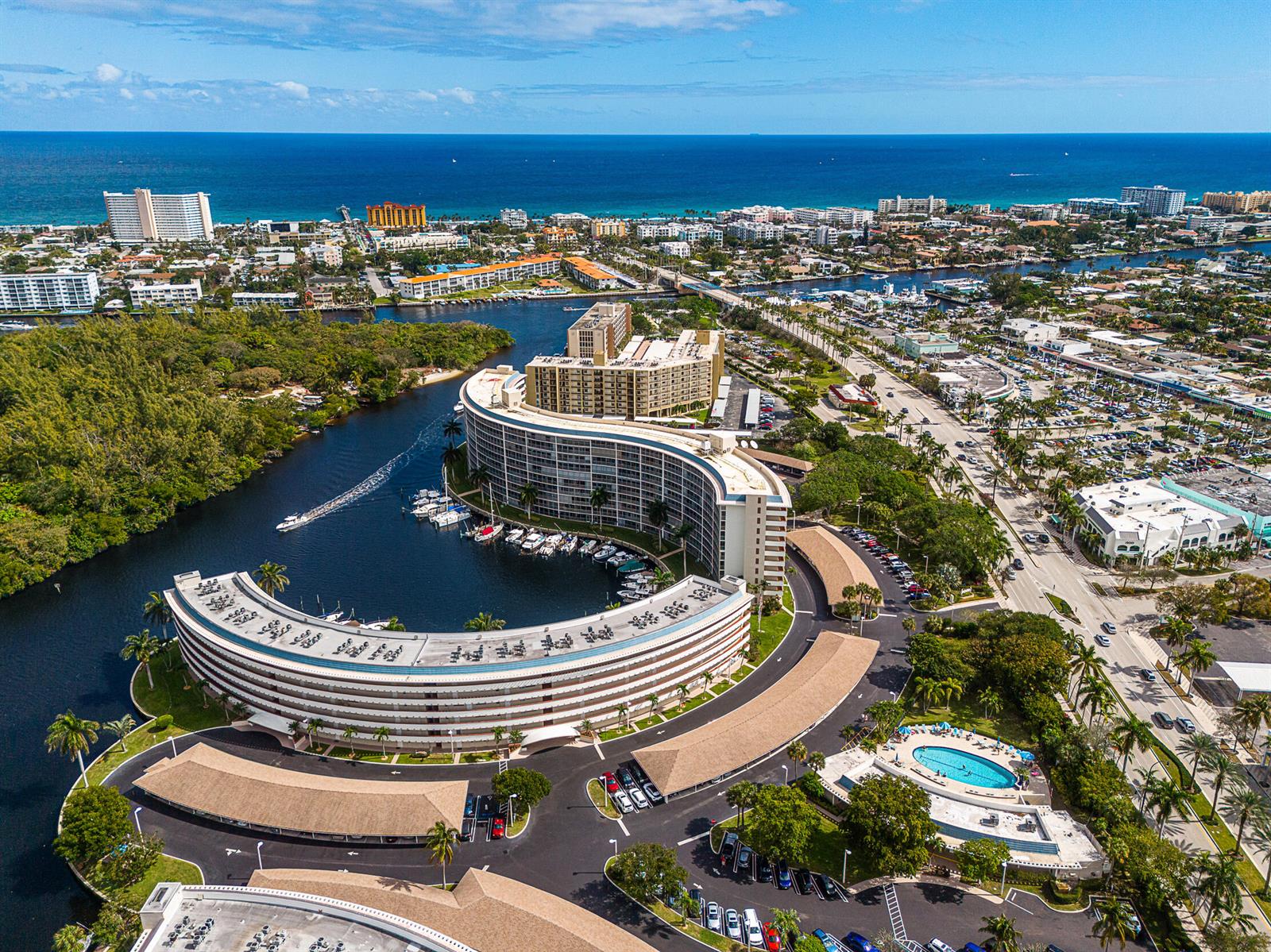 An aerial view shows a curved residential building complex with a marina and swimming pool — 1537 E Hillsboro Boulevard # 243, Deerfield Beach FL 33441, DEERFIELD BEACH, FL