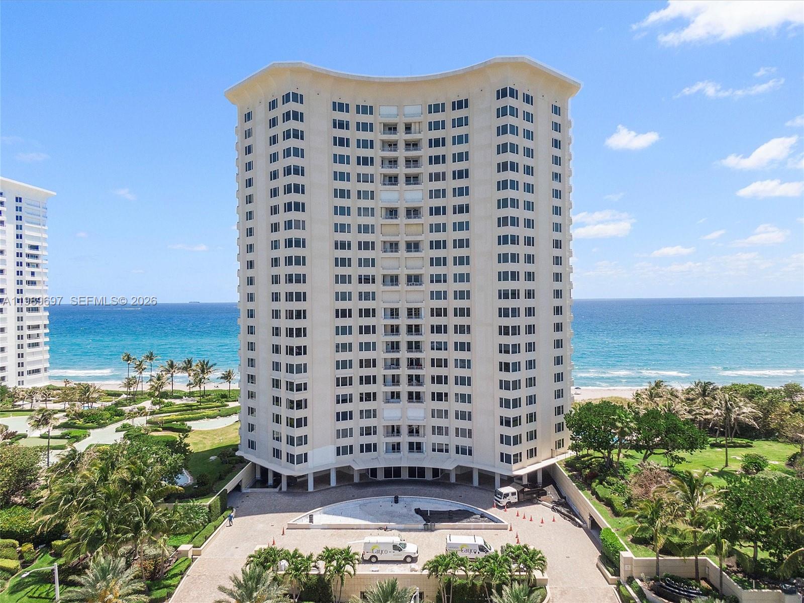 An aerial view of a tall, curved residential building situated on a beach — 550 S Ocean Blvd # 1509, Boca Raton FL 33432, BOCA RATON, FL