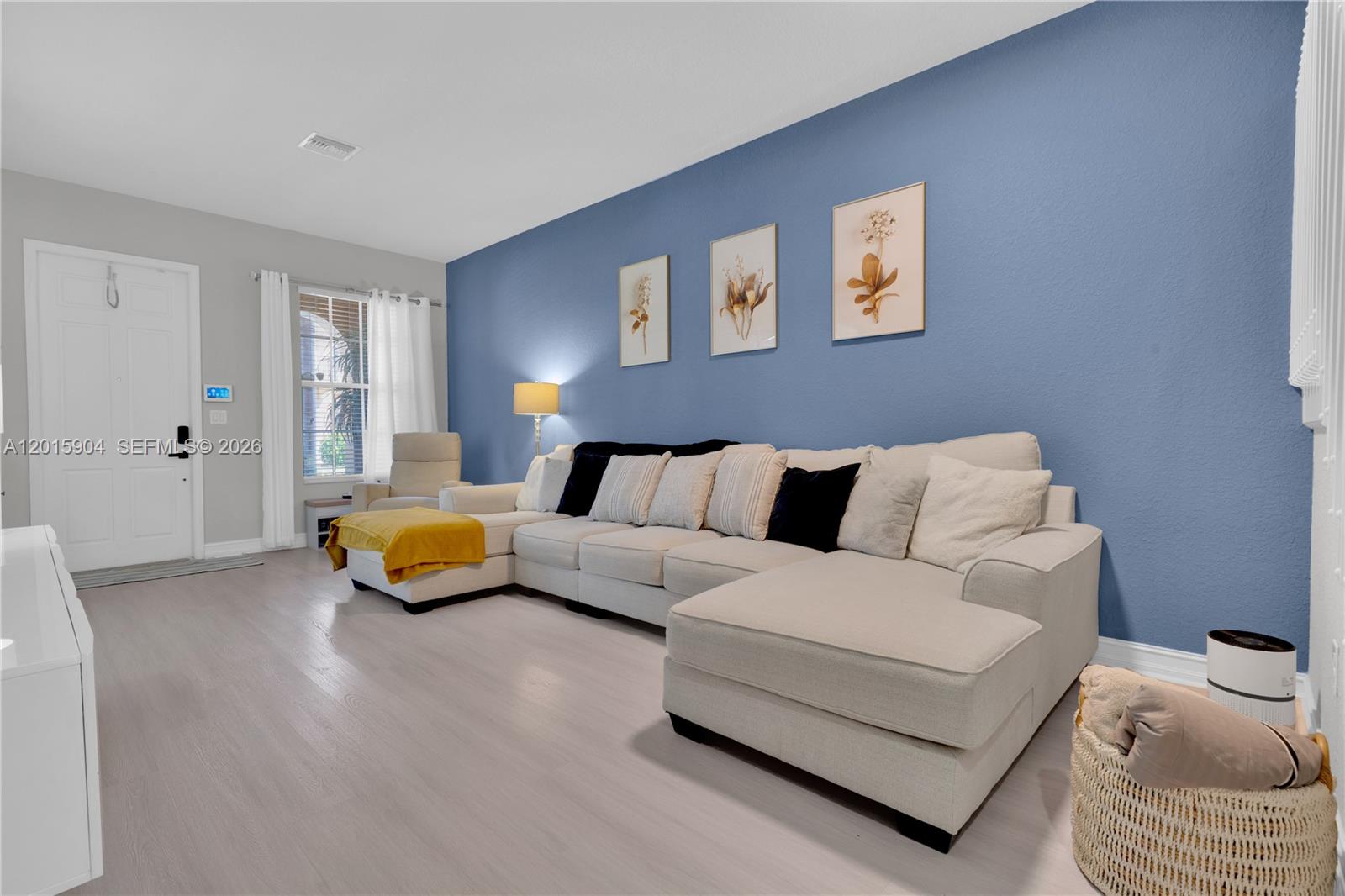 A living room features a large beige sectional sofa against a blue accent wall — 6893 Julia Gardens Dr, Coconut Creek FL 33073, COCONUT CREEK, FL