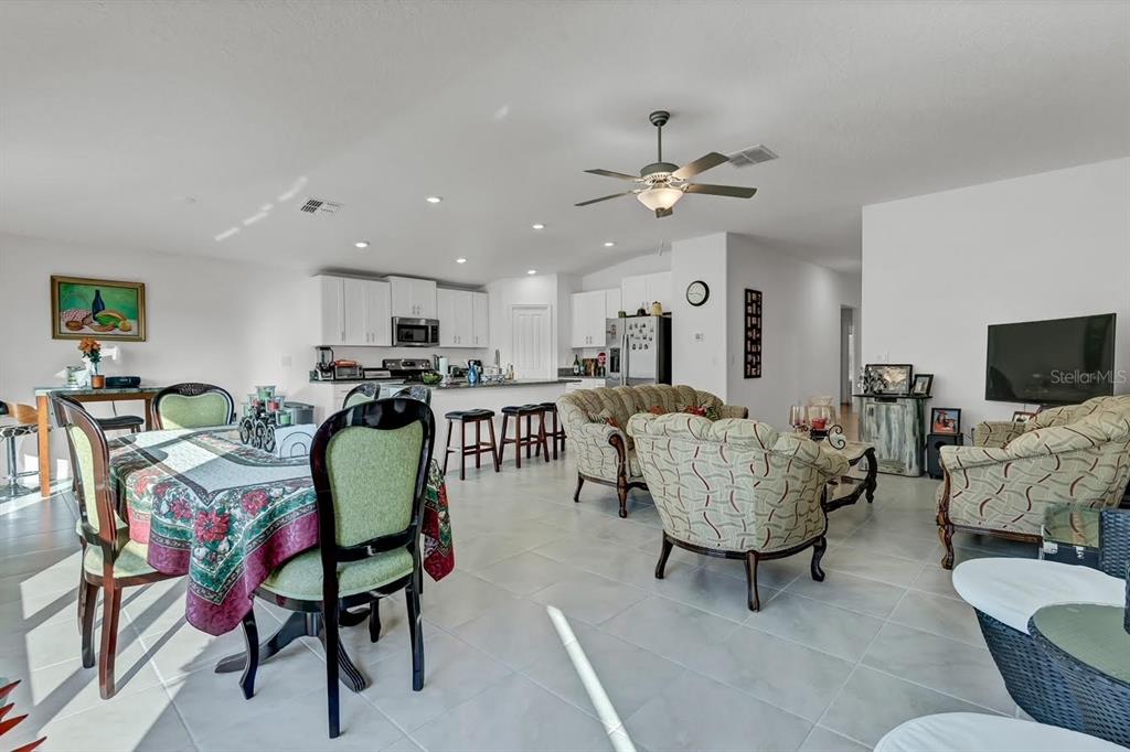 An open-concept living area features a dining set, kitchen with white cabinets, and living room — 6727 BAR S BAR TRAIL, ZEPHYRHILLS, FL