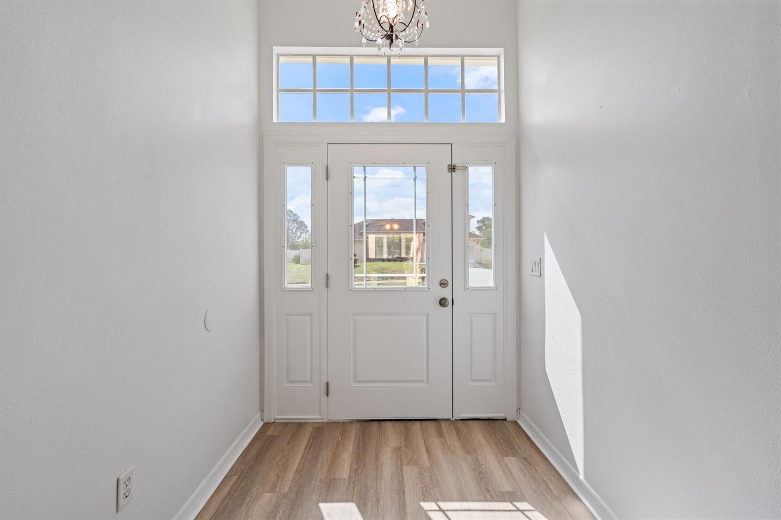 An entryway features a white front door with sidelights, a transom window, and wood-look flooring — 349 Hammock Road SE, Palm Bay FL 32909, PALM BAY, FL