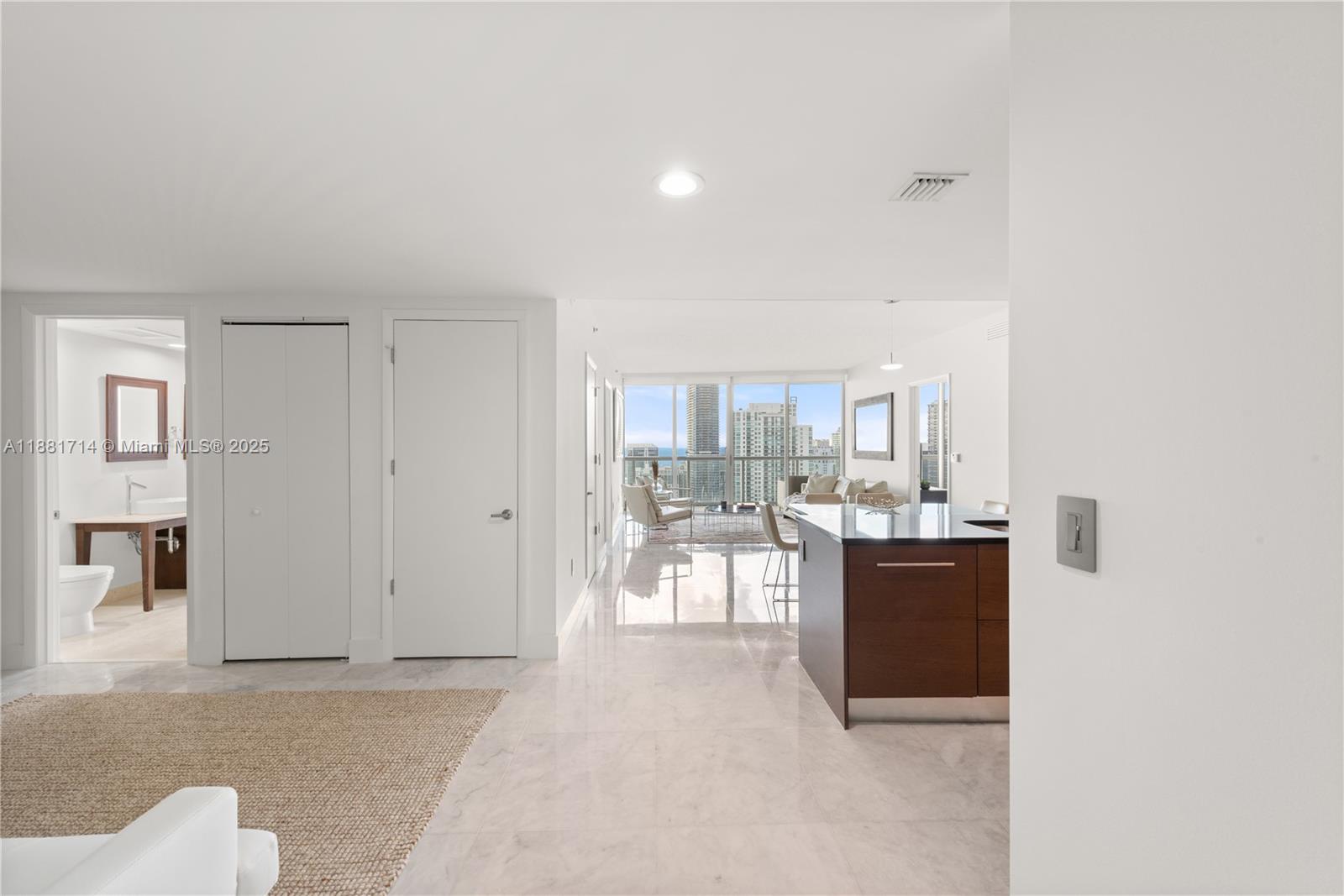 A modern apartment interior features a kitchen island, marble floors, and floor-to-ceiling windows — 495 Brickell Ave # 5003, Miami FL 33131, MIAMI, FL