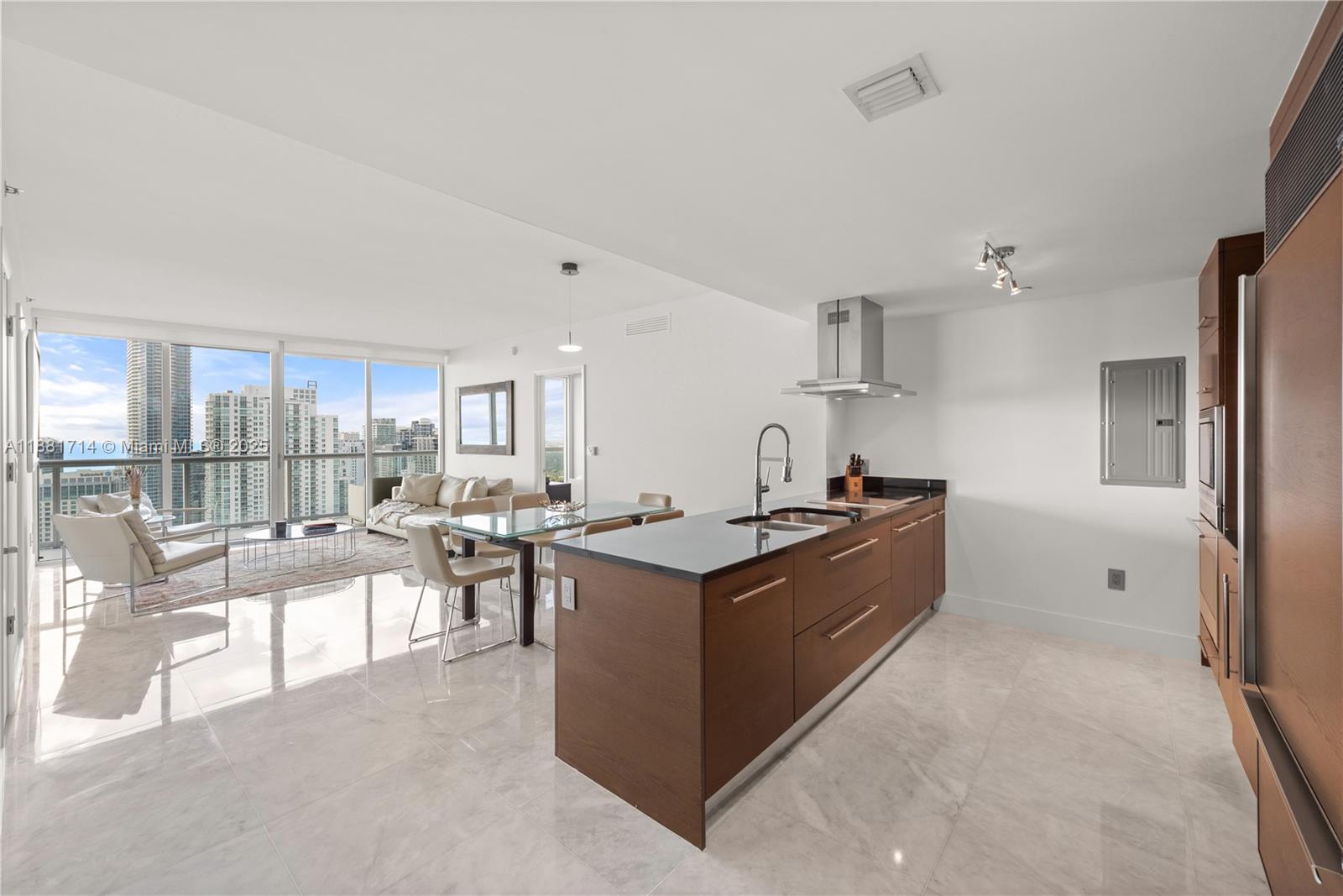 A modern kitchen with a dark wood island and stone countertops opens to a living area — 495 Brickell Ave # 5003, Miami FL 33131, MIAMI, FL