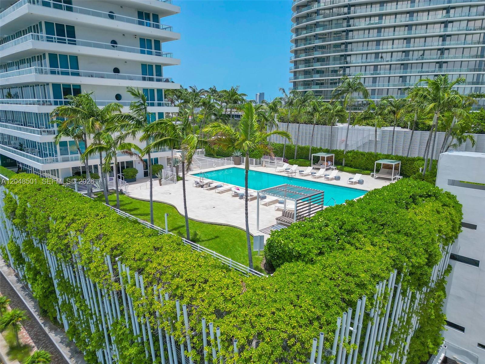An elevated view of a swimming pool area surrounded by palm trees and apartment buildings — 520 West Ave # 604, Miami Beach FL 33139, MIAMI BEACH, FL