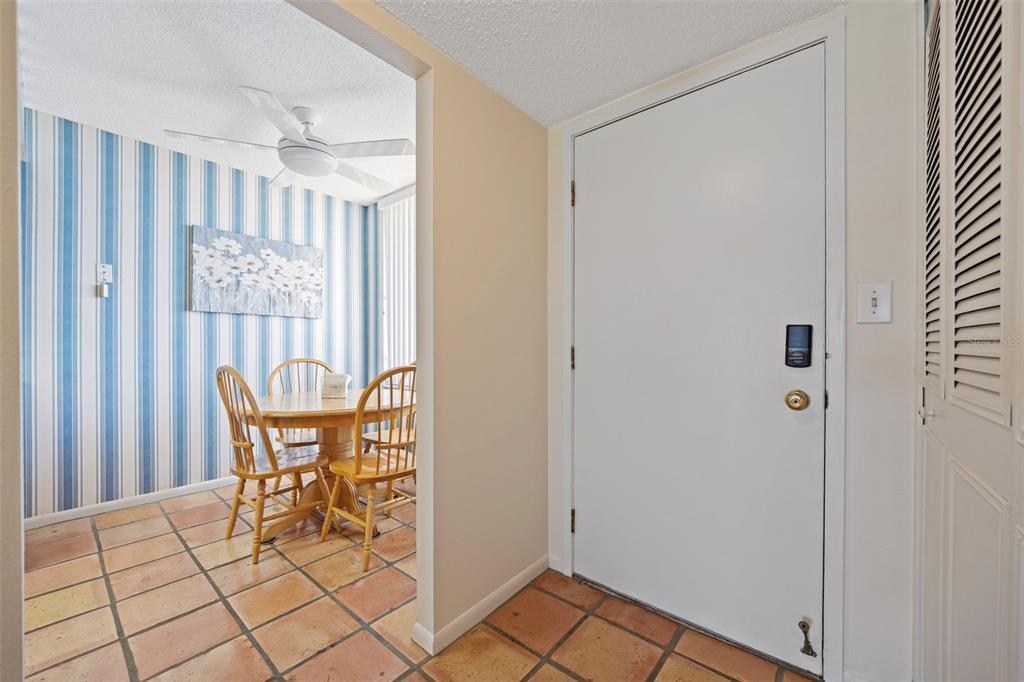 A tiled entryway leads to a dining area with blue-striped wallpaper and a ceiling fan — 9425 BLIND PASS ROAD UNIT 1006, ST PETE BEACH, FL