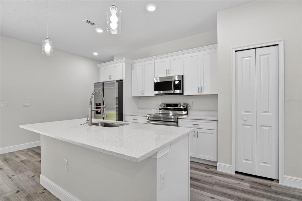 A modern kitchen features white cabinets, stainless steel appliances, and a large quartz-topped island — 7938 N MALTESE DRIVE, CITRUS SPRINGS, FL