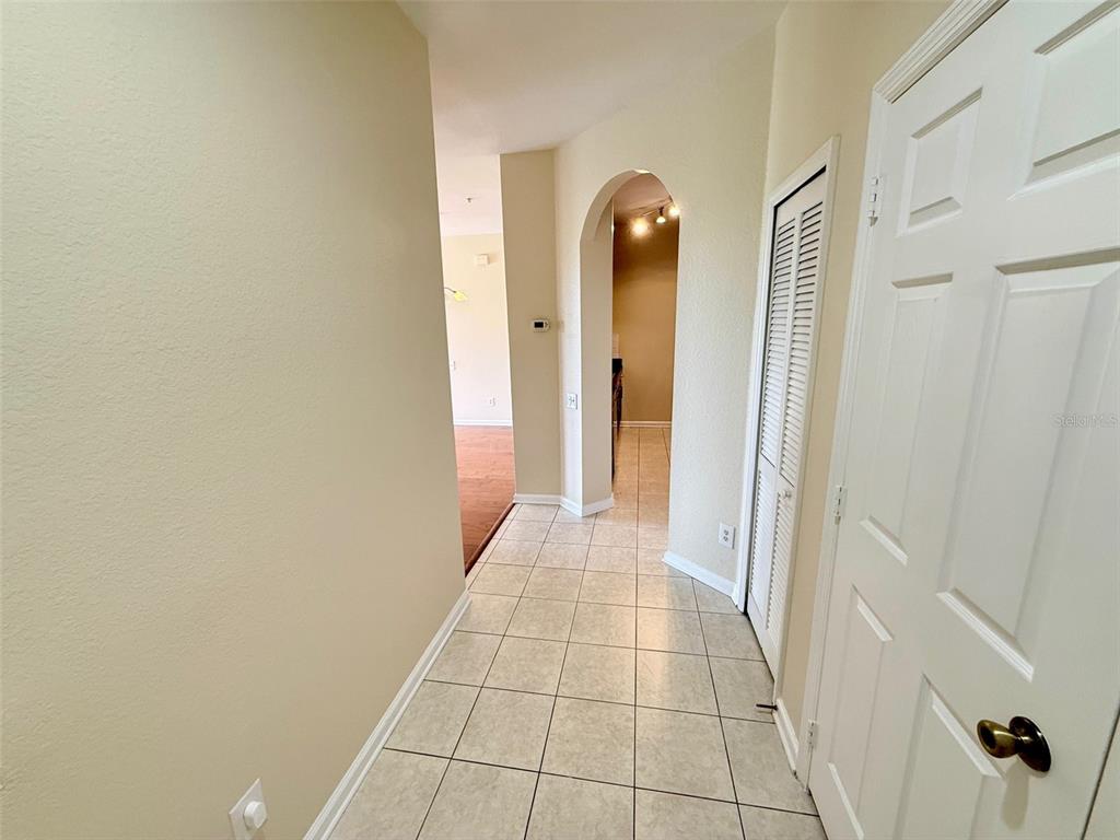 A tiled hallway leads to an arched doorway opening into a kitchen area — 3190 DANTE DRIVE UNIT 301, ORLANDO, FL
