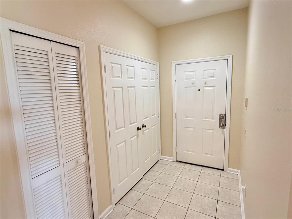 An entryway features tiled flooring, a white front door, and two sets of closet doors — 3190 DANTE DRIVE UNIT 301, ORLANDO, FL