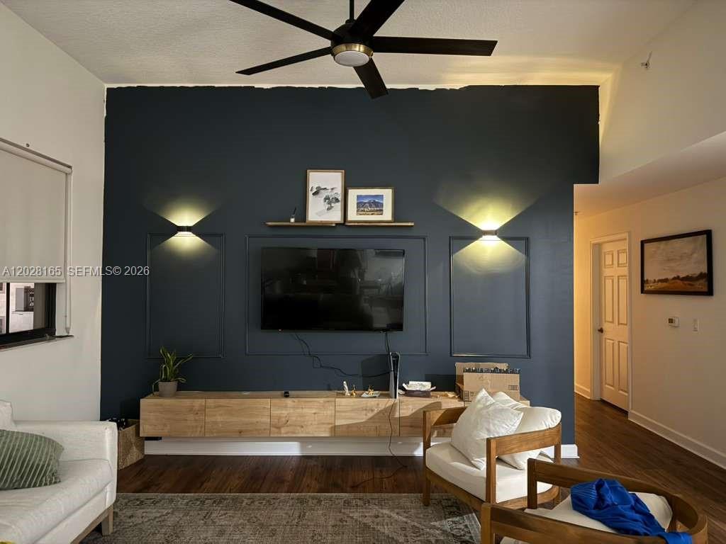 A living room features a dark blue accent wall with molding, a wall-mounted TV, and shelving — 8390 SW 72nd Ave # 519, Miami FL 33143, MIAMI, FL