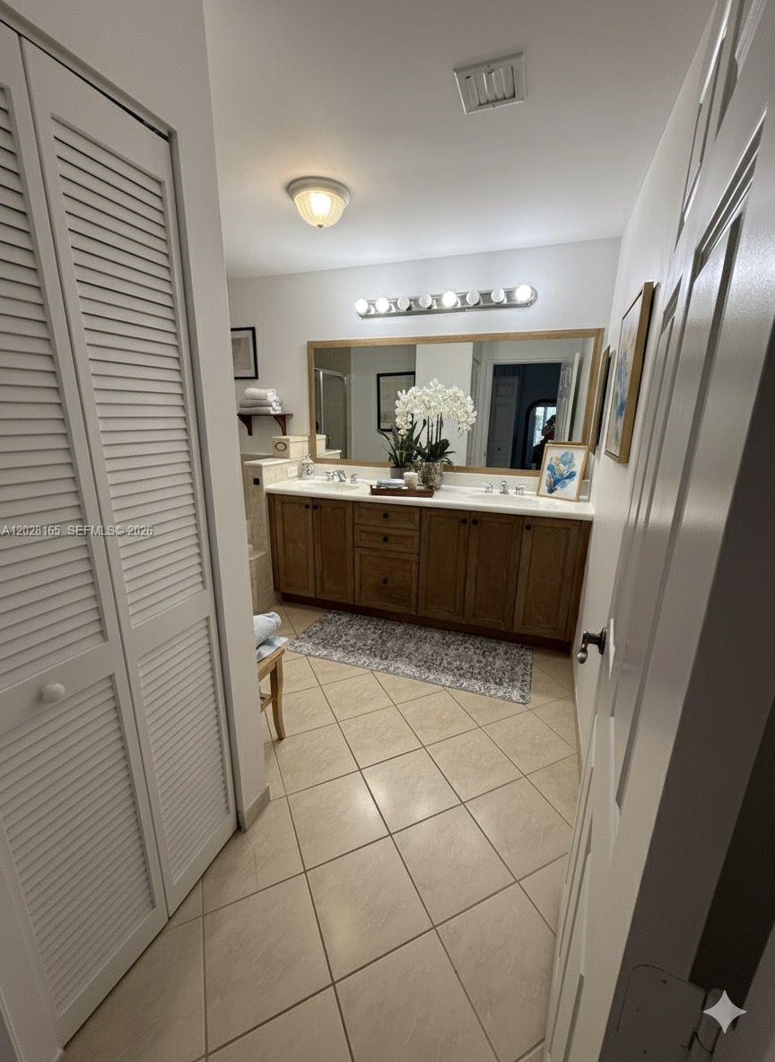 A bathroom features a double vanity with wood cabinets, a large mirror, and tiled flooring — 8390 SW 72nd Ave # 519, Miami FL 33143, MIAMI, FL
