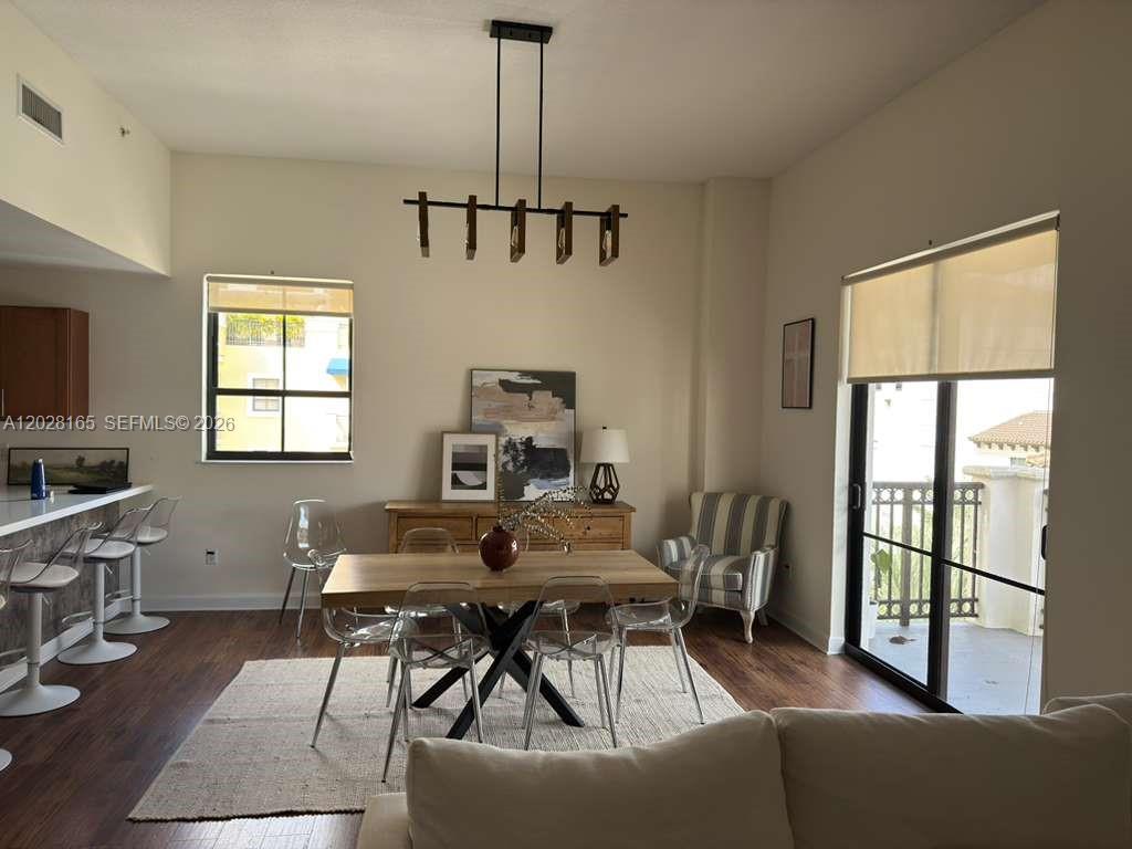 A dining area features a wooden table, clear chairs, a modern chandelier, and a balcony — 8390 SW 72nd Ave # 519, Miami FL 33143, MIAMI, FL