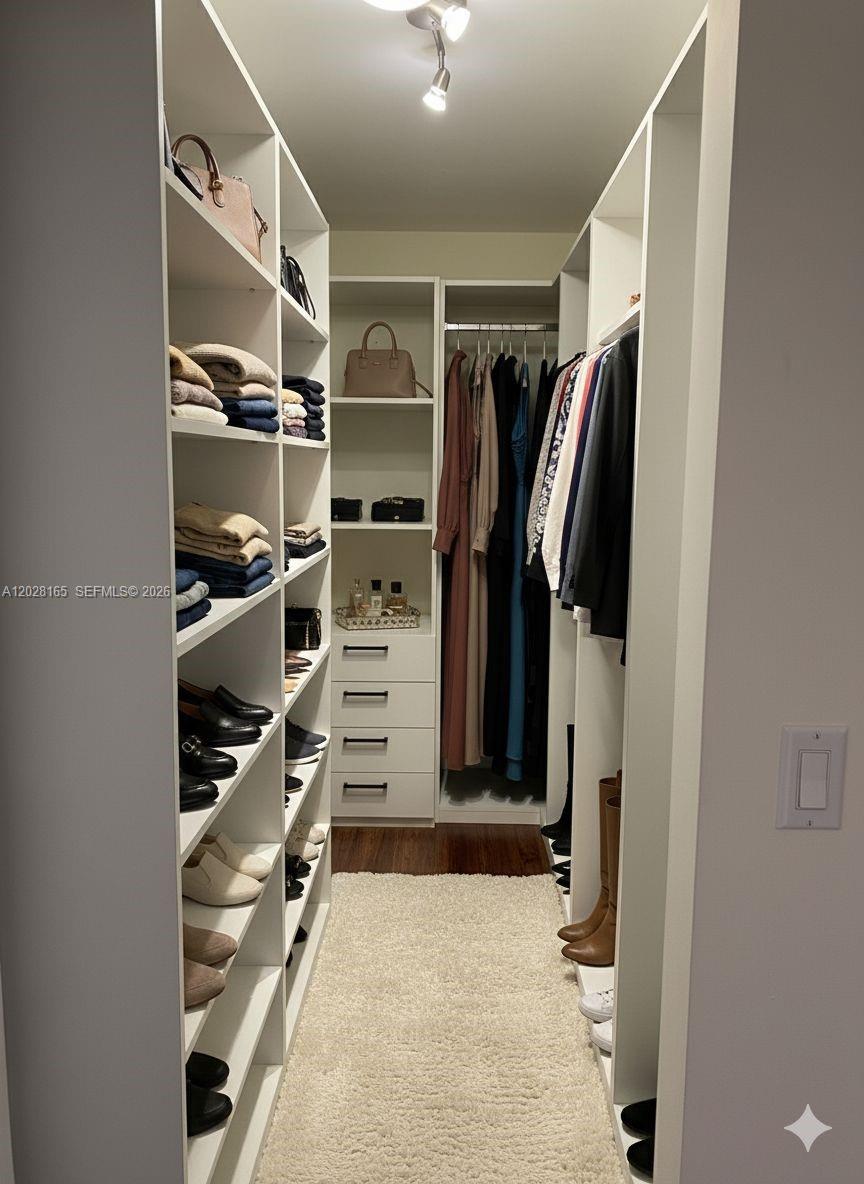 A walk-in closet features white shelving, hanging clothes, drawers, and a plush rug — 8390 SW 72nd Ave # 519, Miami FL 33143, MIAMI, FL