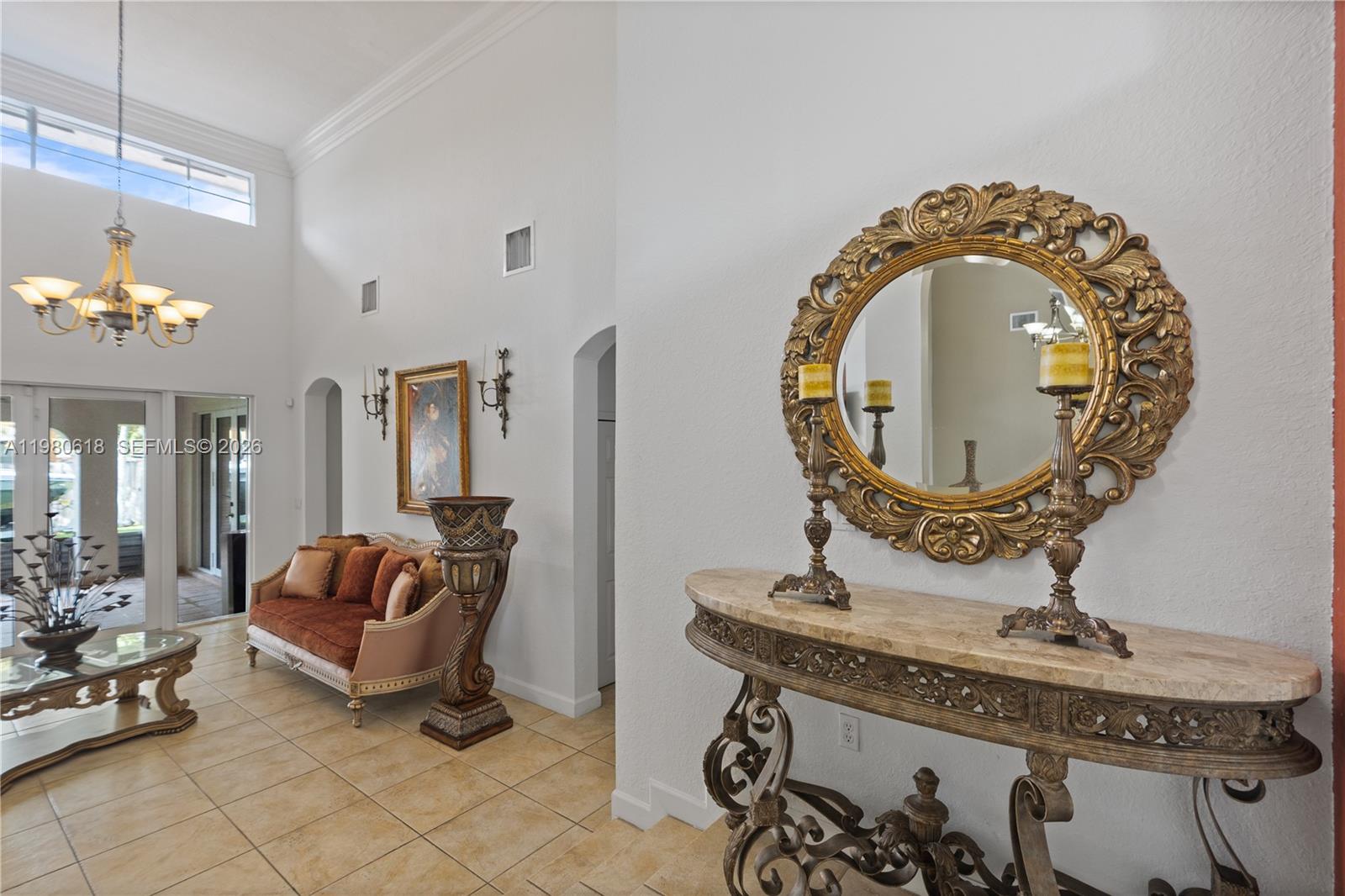 A formal entryway features a marble-topped console table, ornate mirror, and a nearby seating area — 12981 SW 197th St, Miami FL 33177, MIAMI, FL