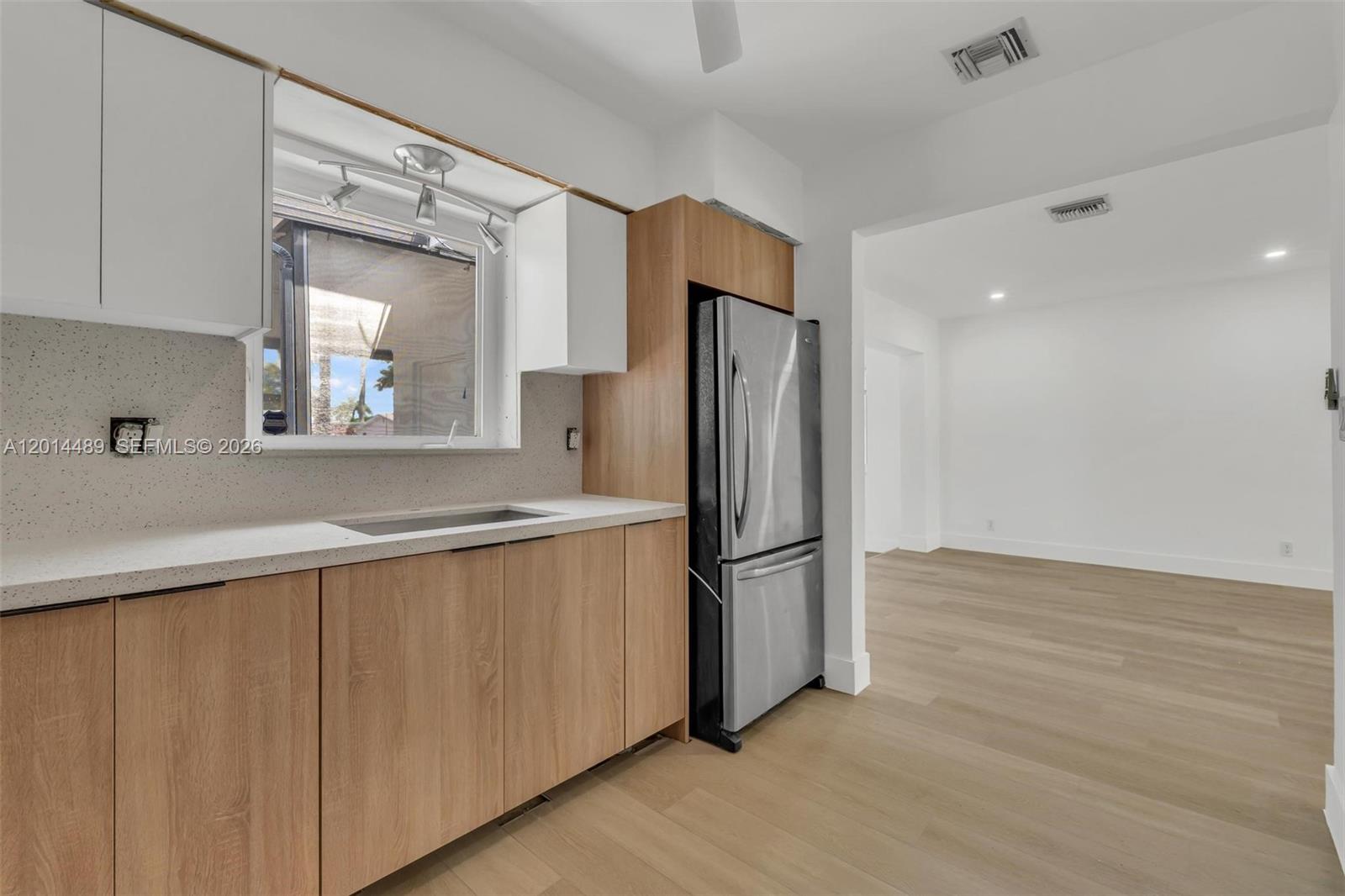A kitchen features light wood cabinets, white countertops, and a stainless steel refrigerator — 1419 Harding St, Hollywood FL 33020, HOLLYWOOD, FL