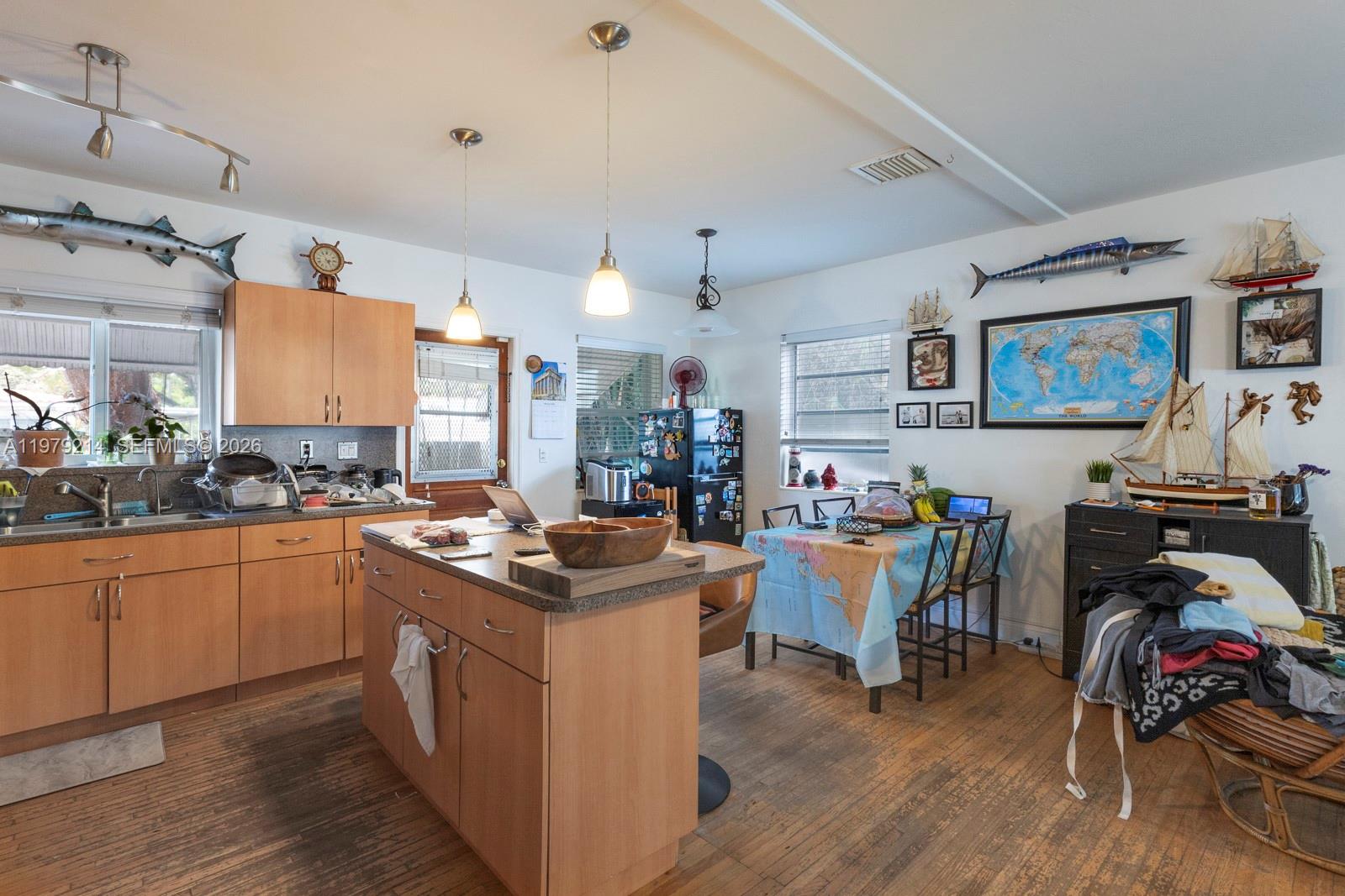 A kitchen with light wood cabinets, a central island, and nautical-themed wall decor — 2710 SW 28th Ct, Miami FL 33133, MIAMI, FL