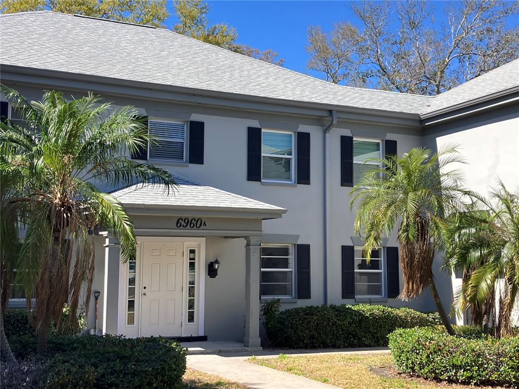 A two-story gray building with a white front door and palm trees in the yard — 6960 A SUNSET DRIVE S UNIT 1C, SOUTH PASADENA, FL