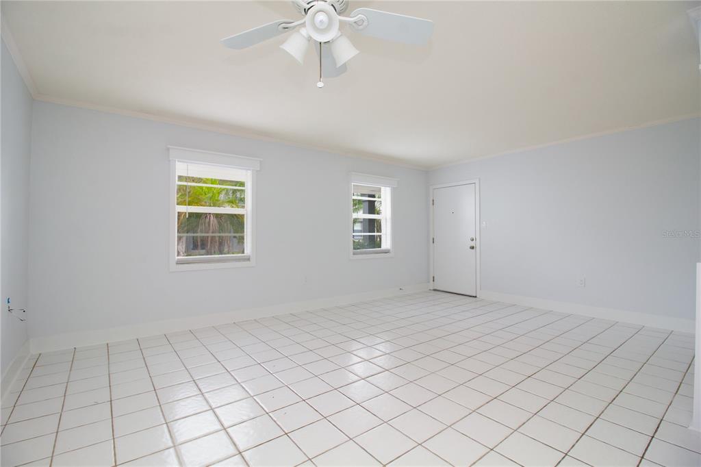 A room with white walls, white tile flooring, a ceiling fan, and two windows — 6960 A SUNSET DRIVE S UNIT 1C, SOUTH PASADENA, FL