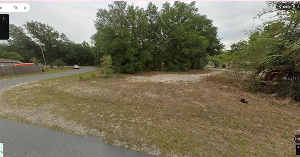 An empty, grassy residential lot sits at the corner of a paved suburban street — 8549 N BUSCETTA LOOP, CRYSTAL RIVER, FL