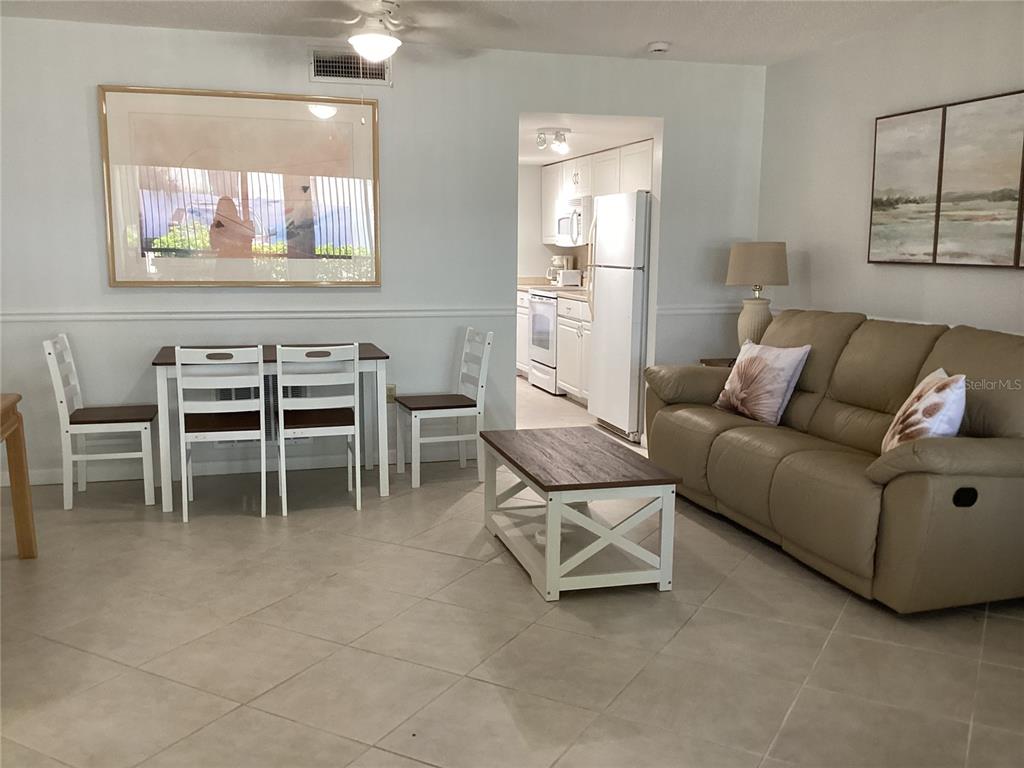 A living and dining area features tile floors, a tan sofa, and a kitchen doorway — 7701 STARKEY ROAD UNIT 703, SEMINOLE, FL
