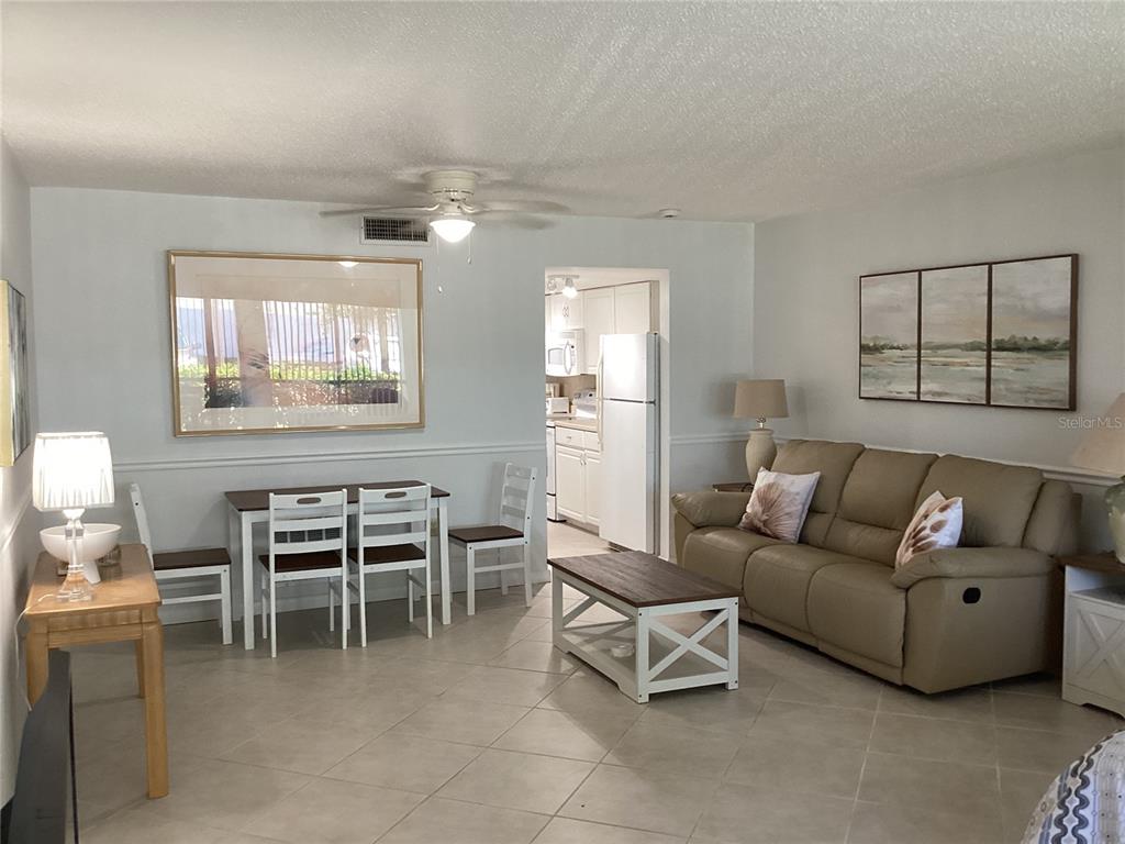 A living and dining area features tile flooring, a beige sofa, and a white table — 7701 STARKEY ROAD UNIT 703, SEMINOLE, FL