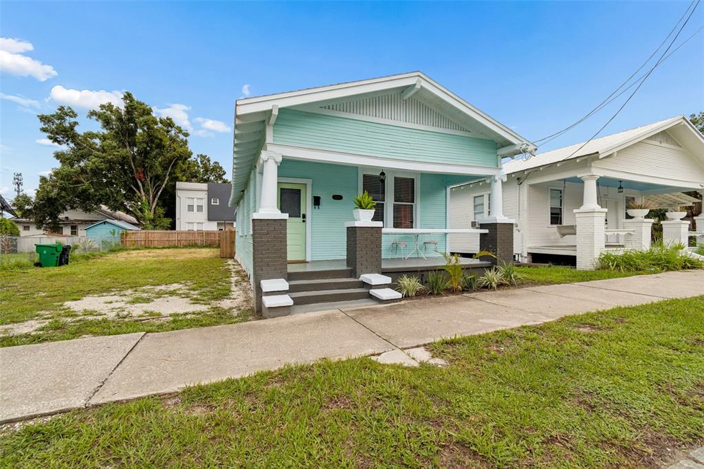A light blue bungalow with a front porch and a vacant lot to the left — 2307 E 11TH AVENUE, TAMPA, FL