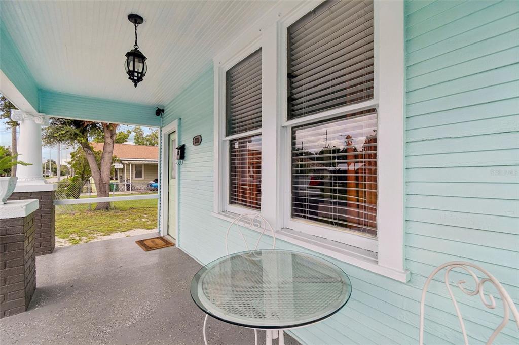 A light blue porch features a glass-topped bistro table, two chairs, and a hanging lantern — 2307 E 11TH AVENUE, TAMPA, FL