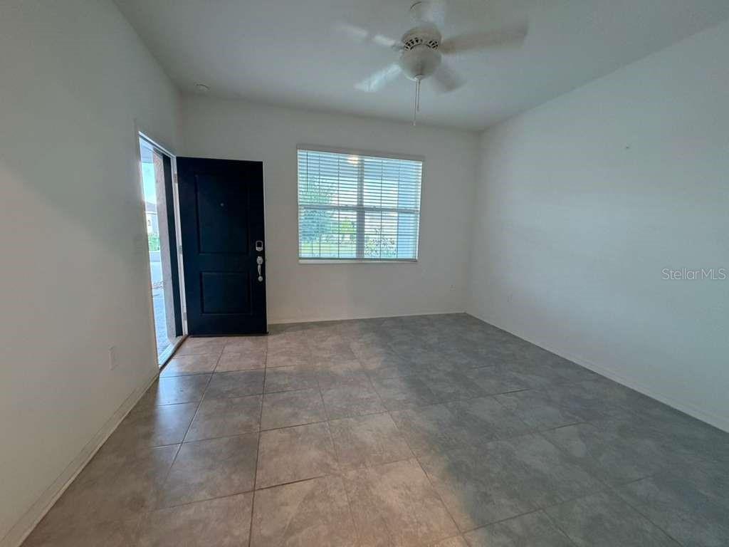 An open front door reveals a view into a bright, tiled interior living space — 1172 TYLER LOOP, WINTER HAVEN, FL
