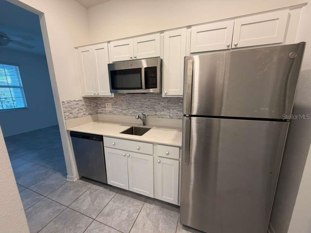 A living room with a beige sofa, a white cabinet, and an adjacent kitchen area — 1172 TYLER LOOP, WINTER HAVEN, FL