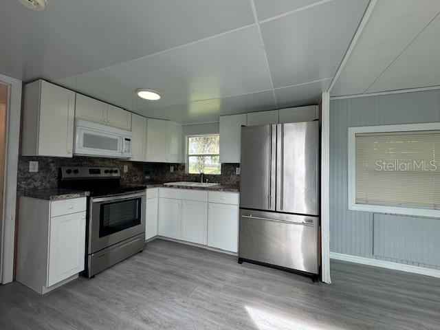 A kitchen features white cabinets, stainless steel appliances, and light wood-look flooring — 6275 - A US HIGHWAY 441 SE, OKEECHOBEE, FL