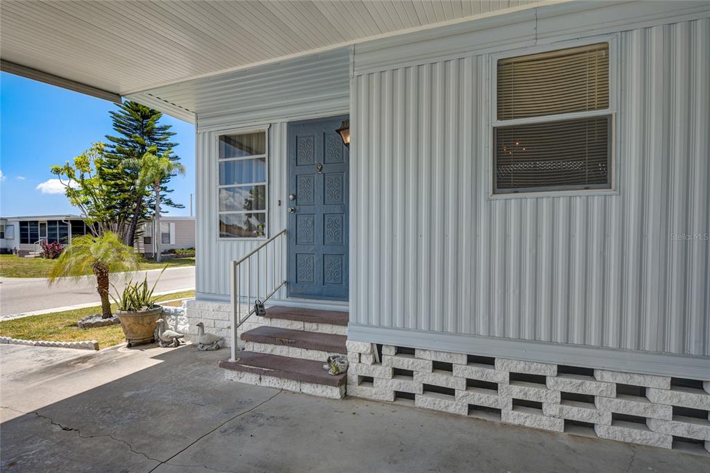 A blue front door with steps and a metal railing sits on a concrete porch — 5619 BAYSHORE ROAD UNIT 312, PALMETTO, FL