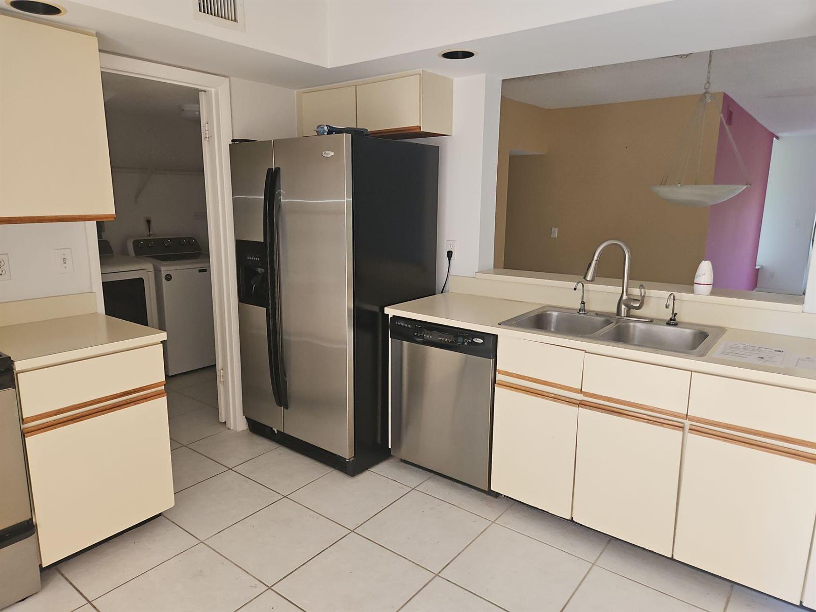 A kitchen features cream cabinets, stainless steel appliances, a double sink, and tiled flooring — 7757 La Mirada Drive, Boca Raton FL 33433, BOCA RATON, FL