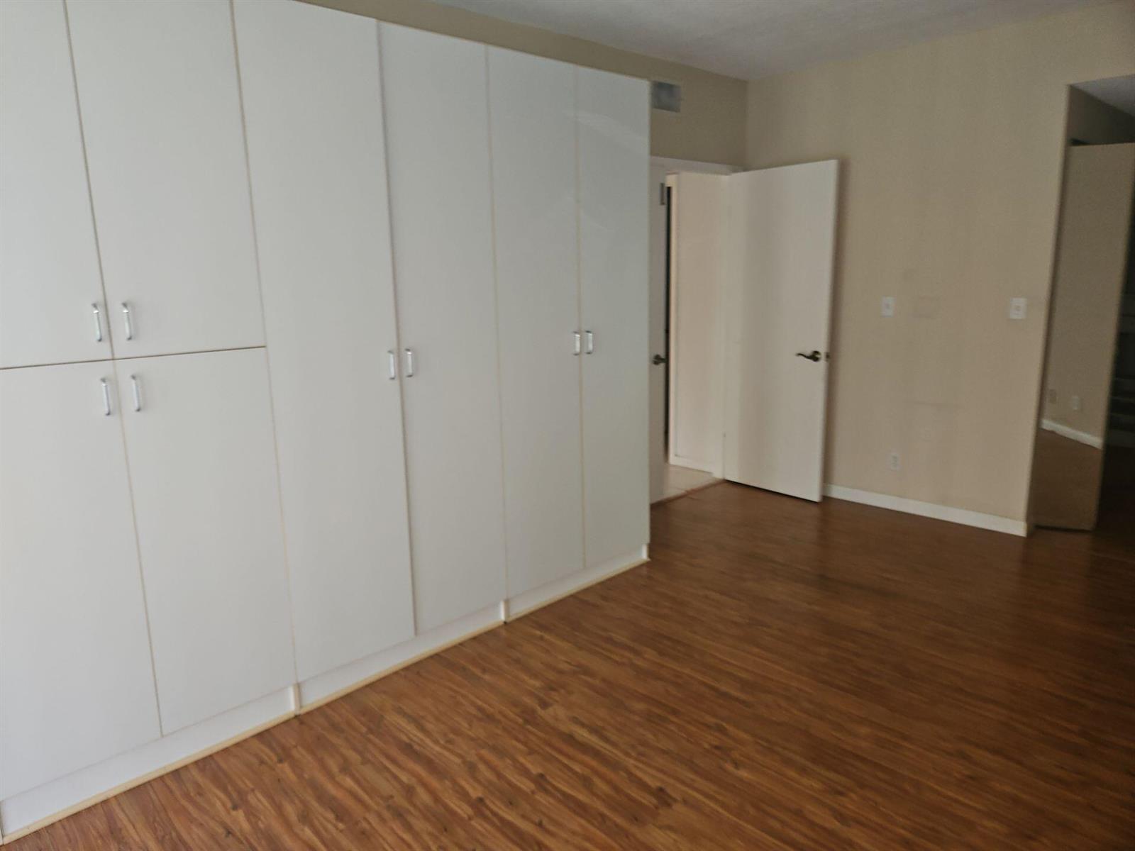 A room with wood-look flooring and a large wall of white built-in storage cabinets — 7757 La Mirada Drive, Boca Raton FL 33433, BOCA RATON, FL