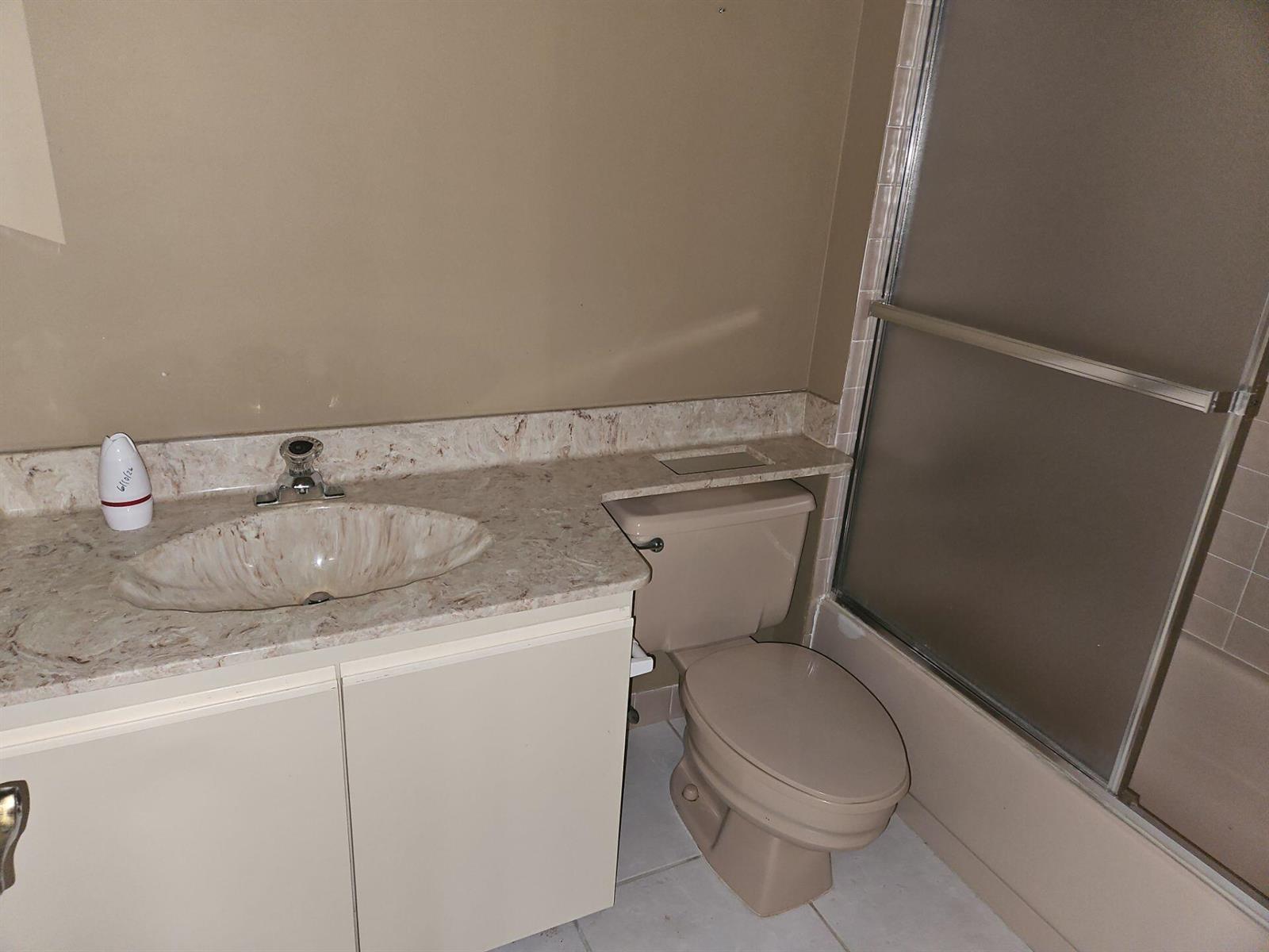 A bathroom features a beige vanity with a stone-look countertop, a toilet, and a shower — 7757 La Mirada Drive, Boca Raton FL 33433, BOCA RATON, FL