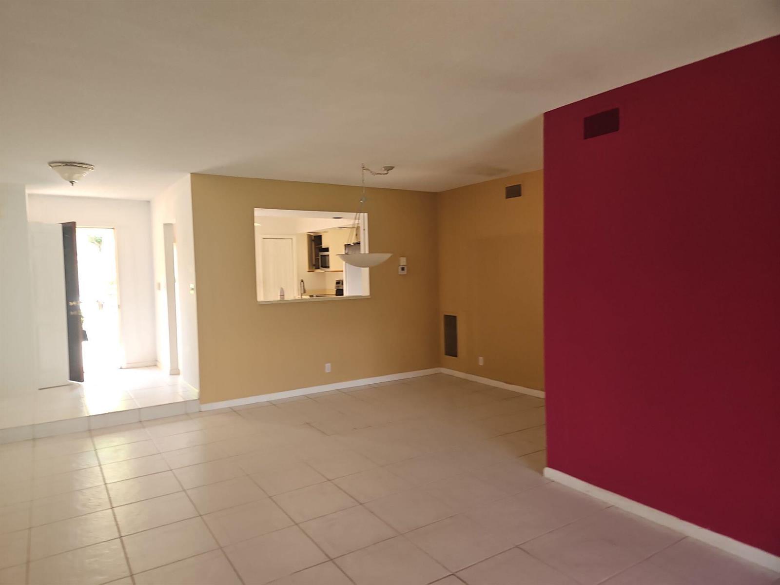 An open living area features light-colored tile floors, tan walls, and a bold red accent wall — 7757 La Mirada Drive, Boca Raton FL 33433, BOCA RATON, FL