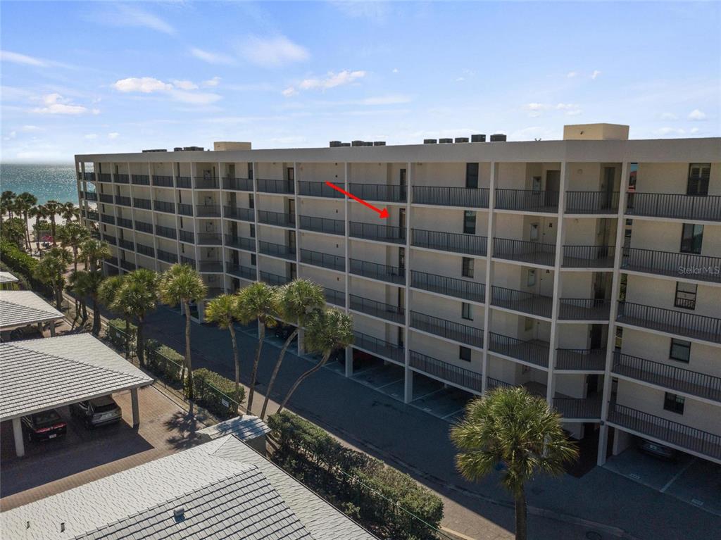 An exterior view of a multi-story apartment building with balconies and a parking area — 6266 MIDNIGHT PASS ROAD UNIT 404, SARASOTA, FL