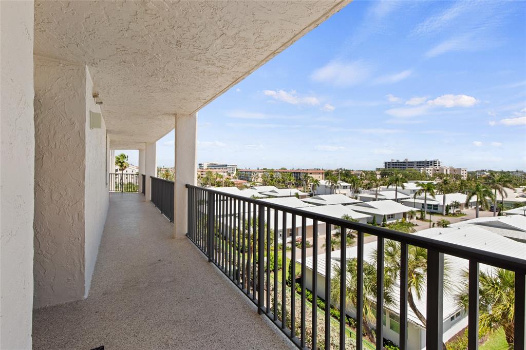 A covered balcony with a metal railing overlooks a neighborhood of houses and palm trees — 6266 MIDNIGHT PASS ROAD UNIT 404, SARASOTA, FL