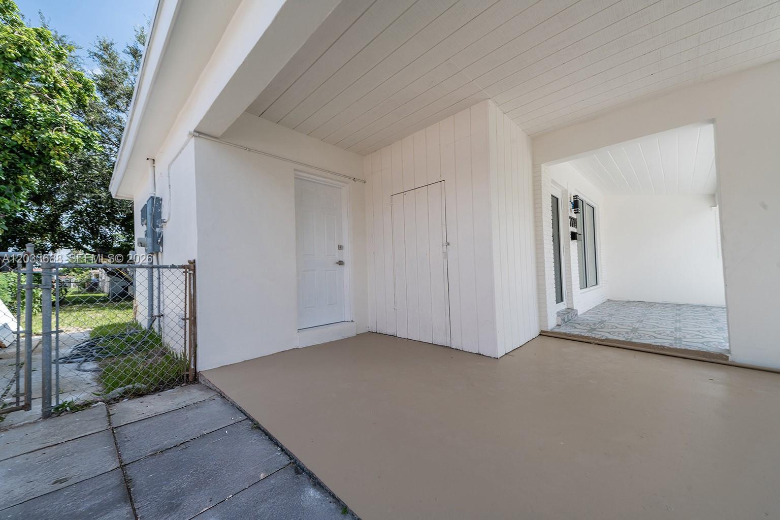 A covered concrete patio area features a white door, a storage closet, and a fence — 7721 Indigo St, Miramar FL 33023, MIRAMAR, FL