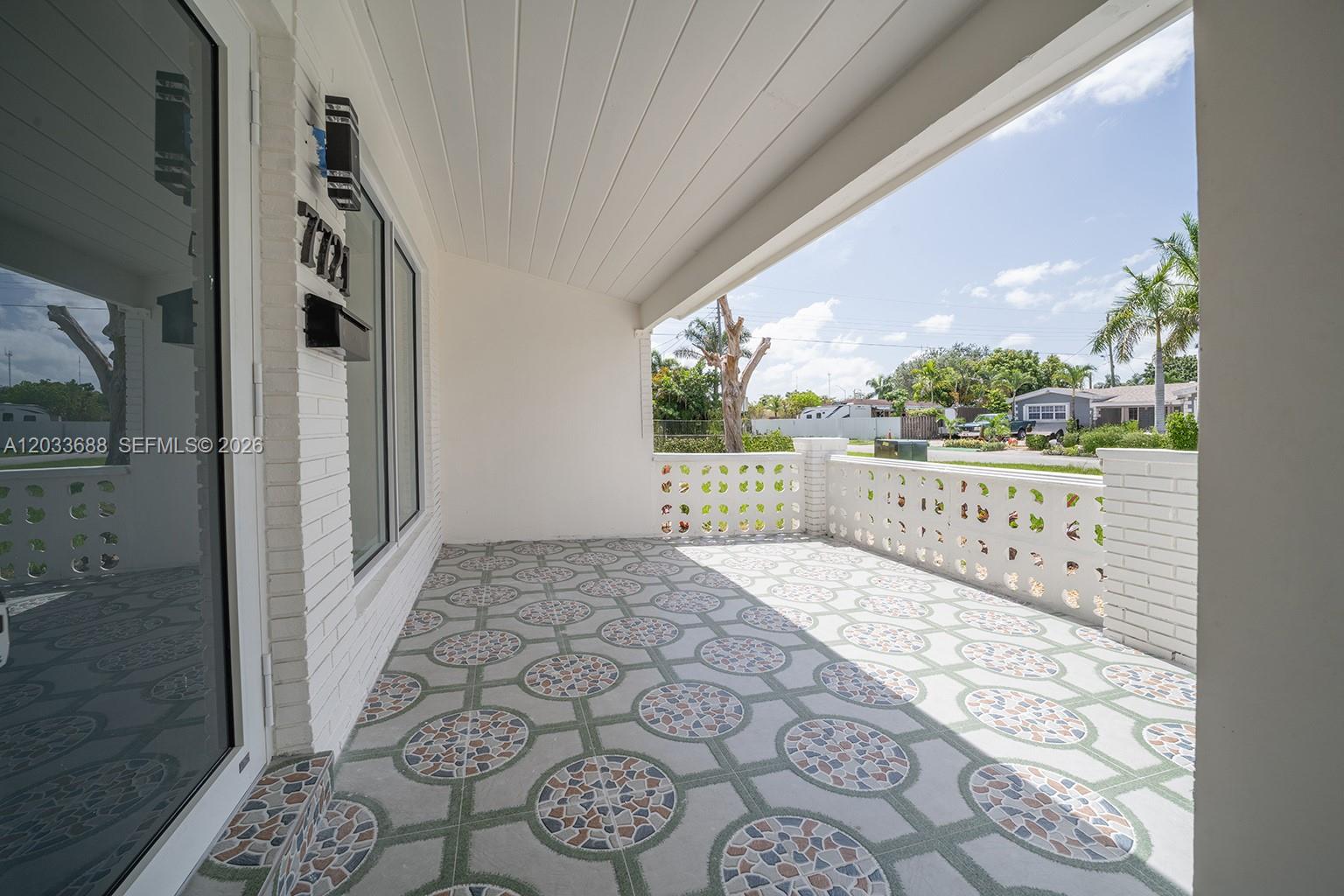 A covered front porch features patterned tile flooring and a decorative white brick railing — 7721 Indigo St, Miramar FL 33023, MIRAMAR, FL
