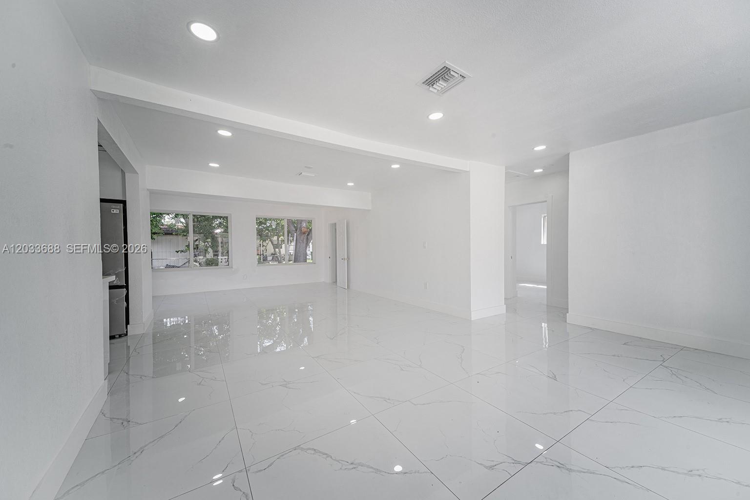 A bright, open-concept living area features white walls, recessed lighting, and polished marble-look tile flooring — 7721 Indigo St, Miramar FL 33023, MIRAMAR, FL