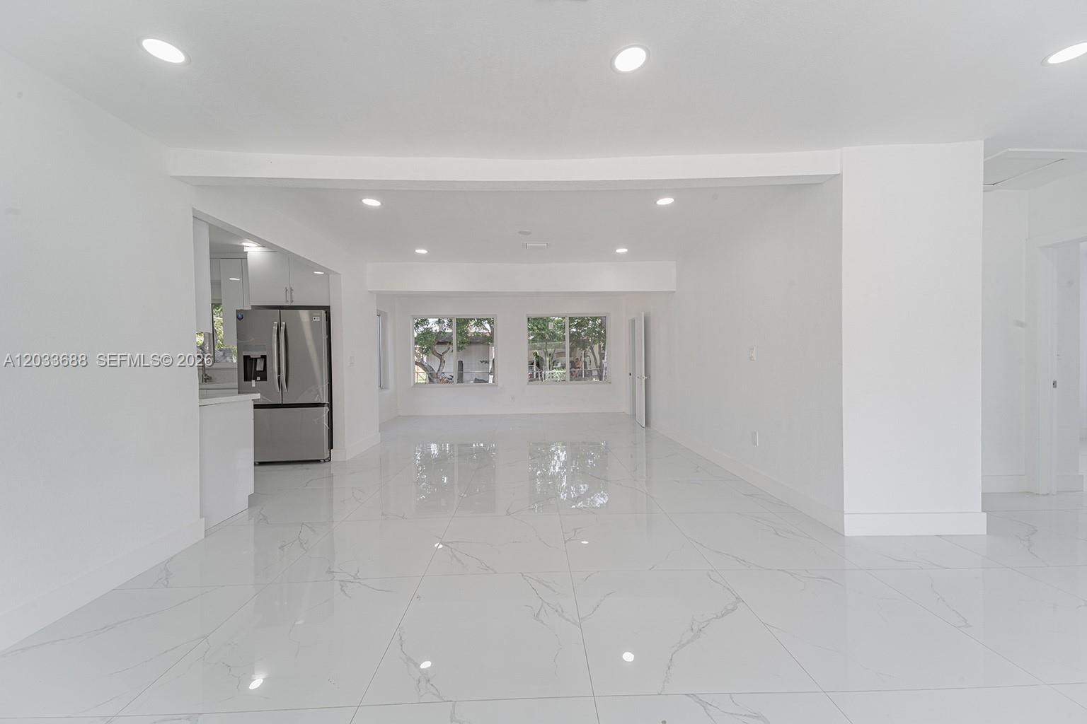 A bright, open-concept living area features white walls, recessed lighting, and polished marble-look tile flooring — 7721 Indigo St, Miramar FL 33023, MIRAMAR, FL