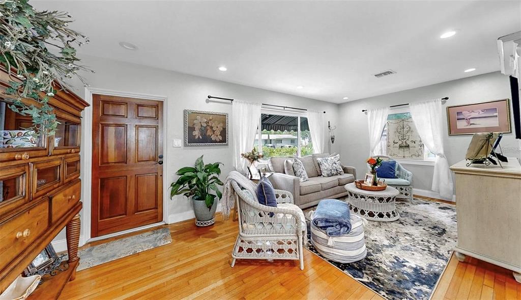 A living room features hardwood floors, a wooden front door, and a gray sofa — 4020 QUEEN STREET N, ST PETERSBURG, FL