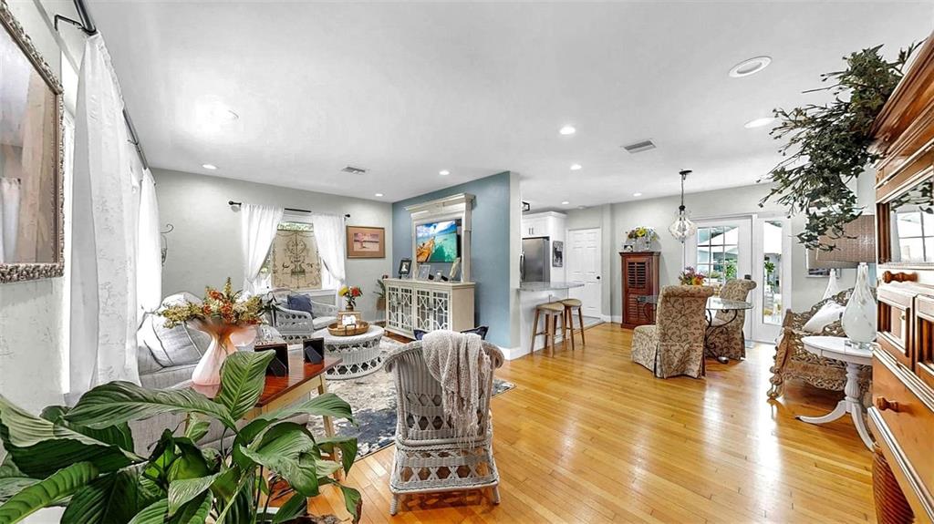 An open-concept living and dining area features hardwood floors, a blue accent wall, and furniture — 4020 QUEEN STREET N, ST PETERSBURG, FL
