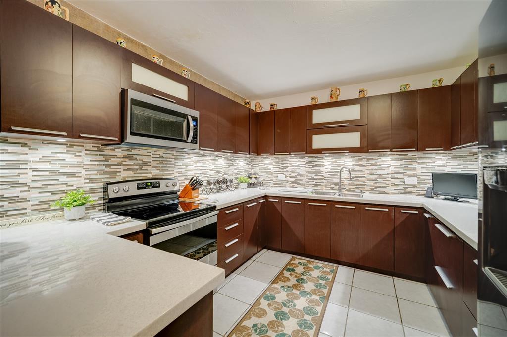 A kitchen features dark wood cabinets, light countertops, a tiled backsplash, and stainless steel appliances — Carretera 715 KILOMETRO 3.7, CAYEY, PR