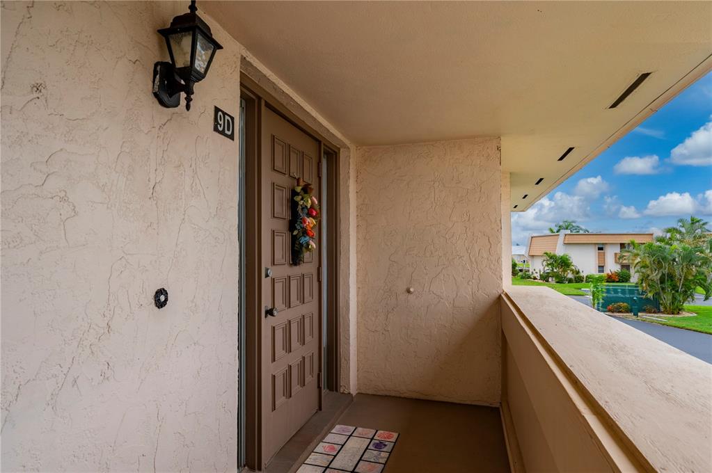 An exterior view of a residential unit entrance with a brown door and balcony — 1080 BAL HARBOR BOULEVARD UNIT 9D, PUNTA GORDA, FL