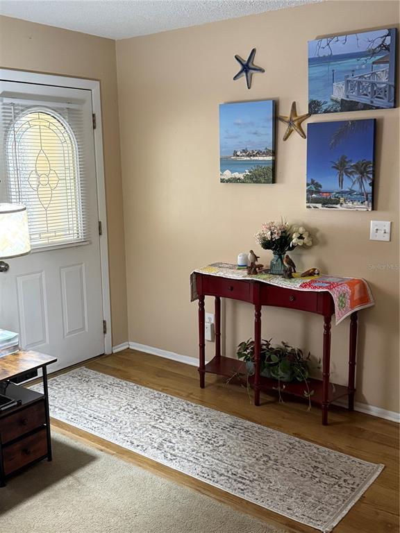 An entryway features a red console table, wall art, and a runner rug on wood floors — 5517 WESTBROOK DRIVE, ORLANDO, FL