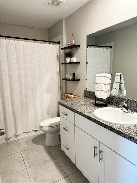 A kitchen with white cabinets, a granite island, and a dining area with black chairs — 6131 SPRING CRAYFISH AVENUE, NEW PORT RICHEY, FL